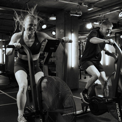 Two people exercising on stationary bikes in a gym setting.